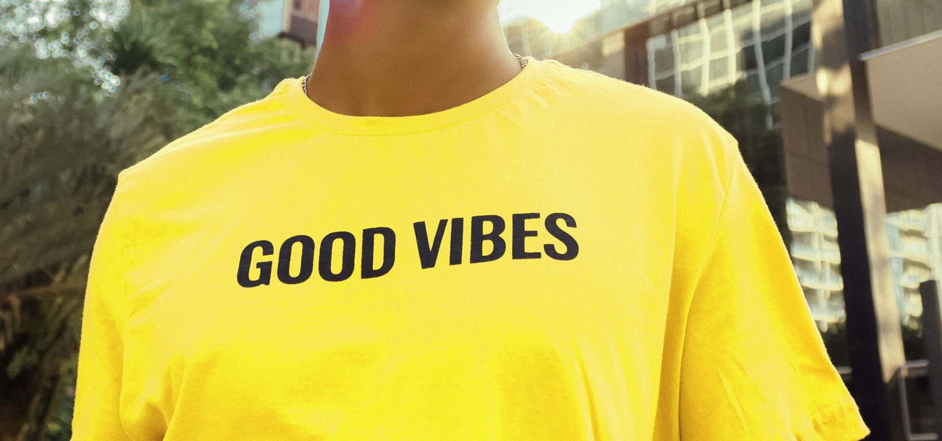 Man in yellow t-shirt with the text 'GOOD VIBES'