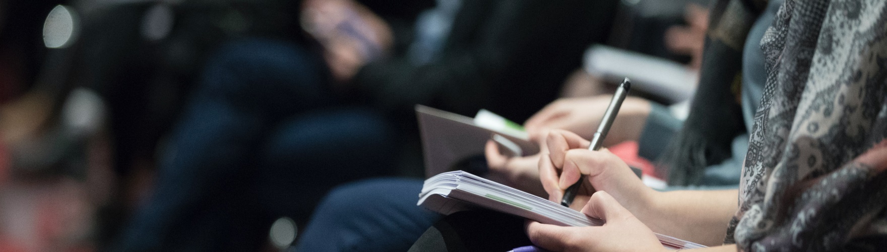 Person taking notes during conference.