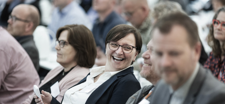 Business woman sitting in a crowd laughing.